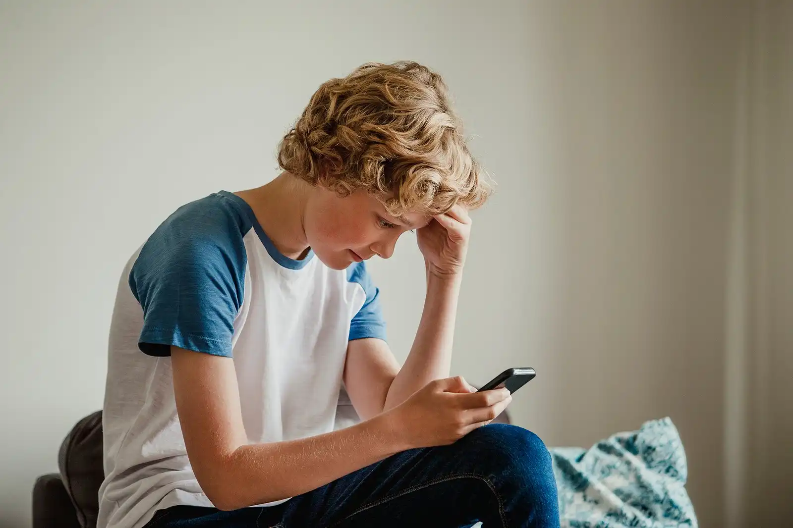 Young Guy head in his hand reading text message Teenager lad on phone